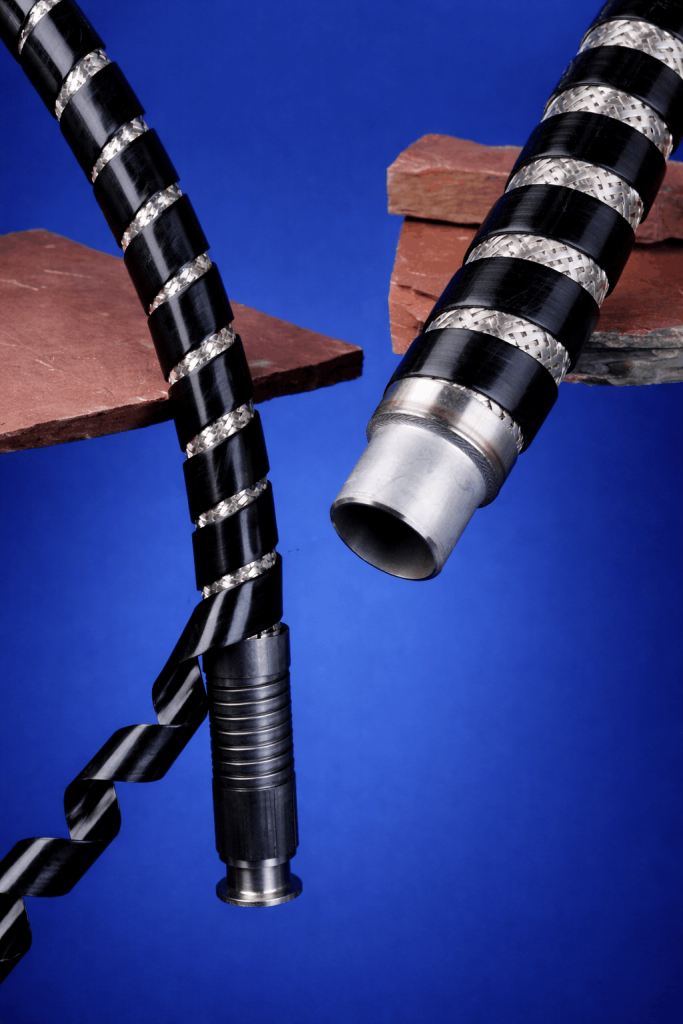 Close-up of black and silver striped industrial hoses twisted between red bricks on a blue background.